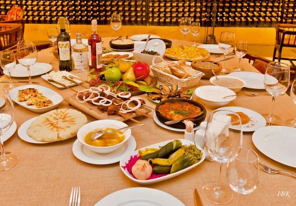 Ein reich gedeckter Tisch mit traditionellen georgischen Spezialitäten wie Schaschlik, Khachapuri, frischem Obst und verschiedenen Vorspeisen in einer authentischen Umgebung.